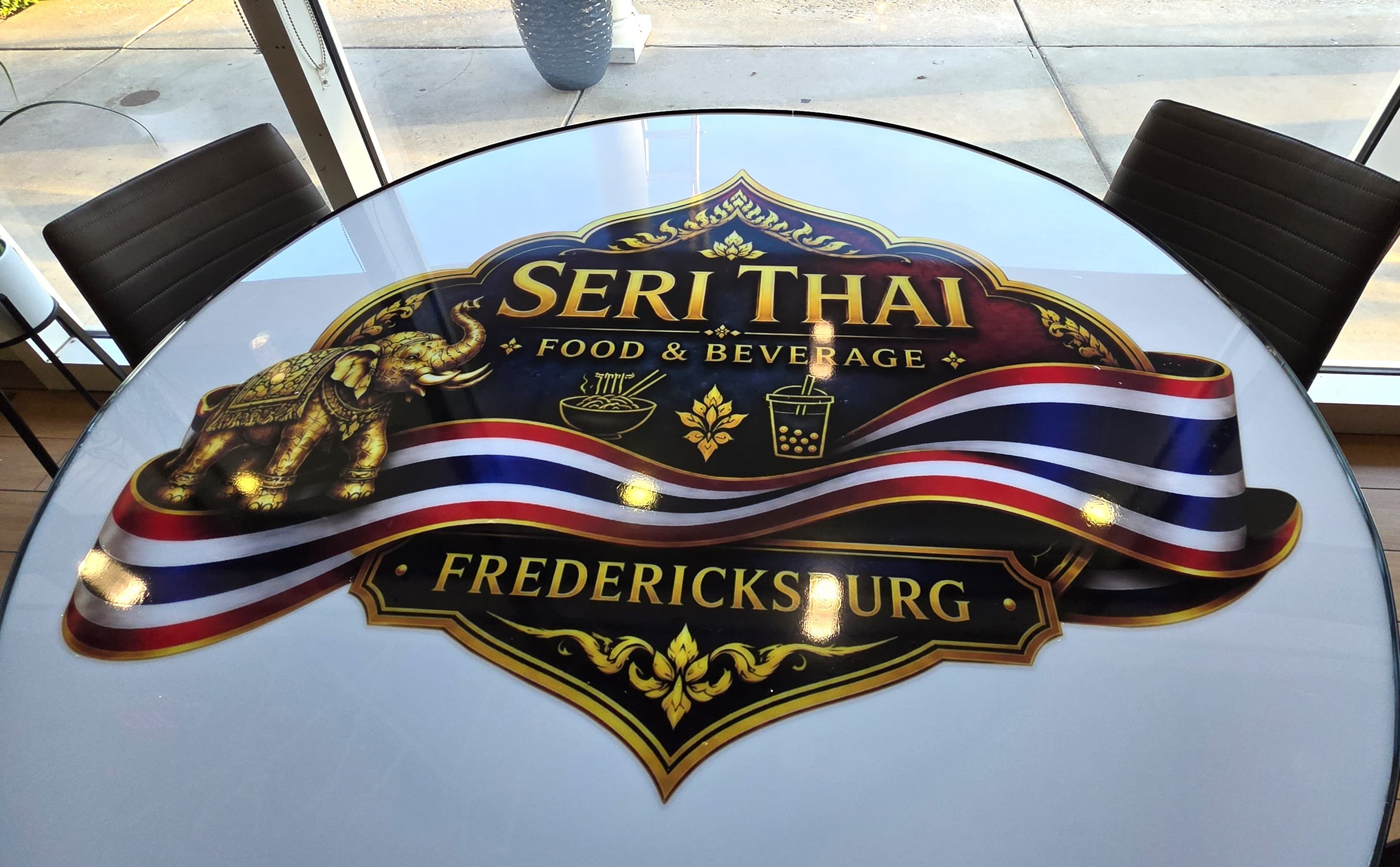 Seri Thai logo on a white table featuring a golden elephant and Thai flag ribbon.